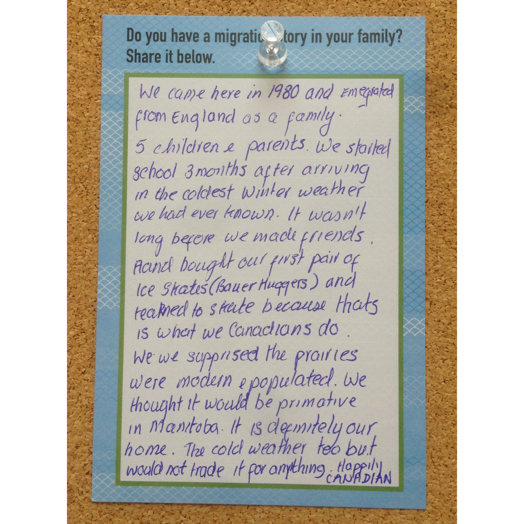 A notecard on a bulletin board sharing an emigration story of a woman who moved with her fromily to Canada from England in 1980. She tells of how they arrived in winter, and bought skates and learned to skate. She shares their surprise at the "modern" and "populated" prairies.