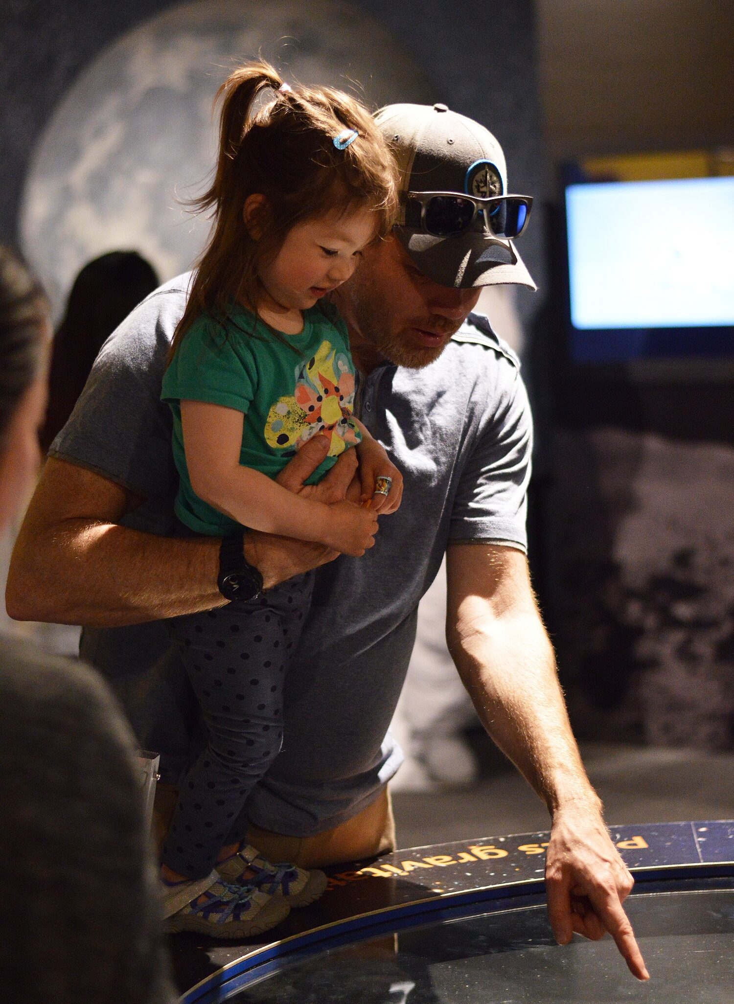 An adult holding a young child as they engage in an exhibit in the Manitoba Museum Science Gallery.