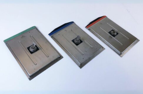 Three metal film holders lying flat on a light surface with green, blue, and red bars across the top.