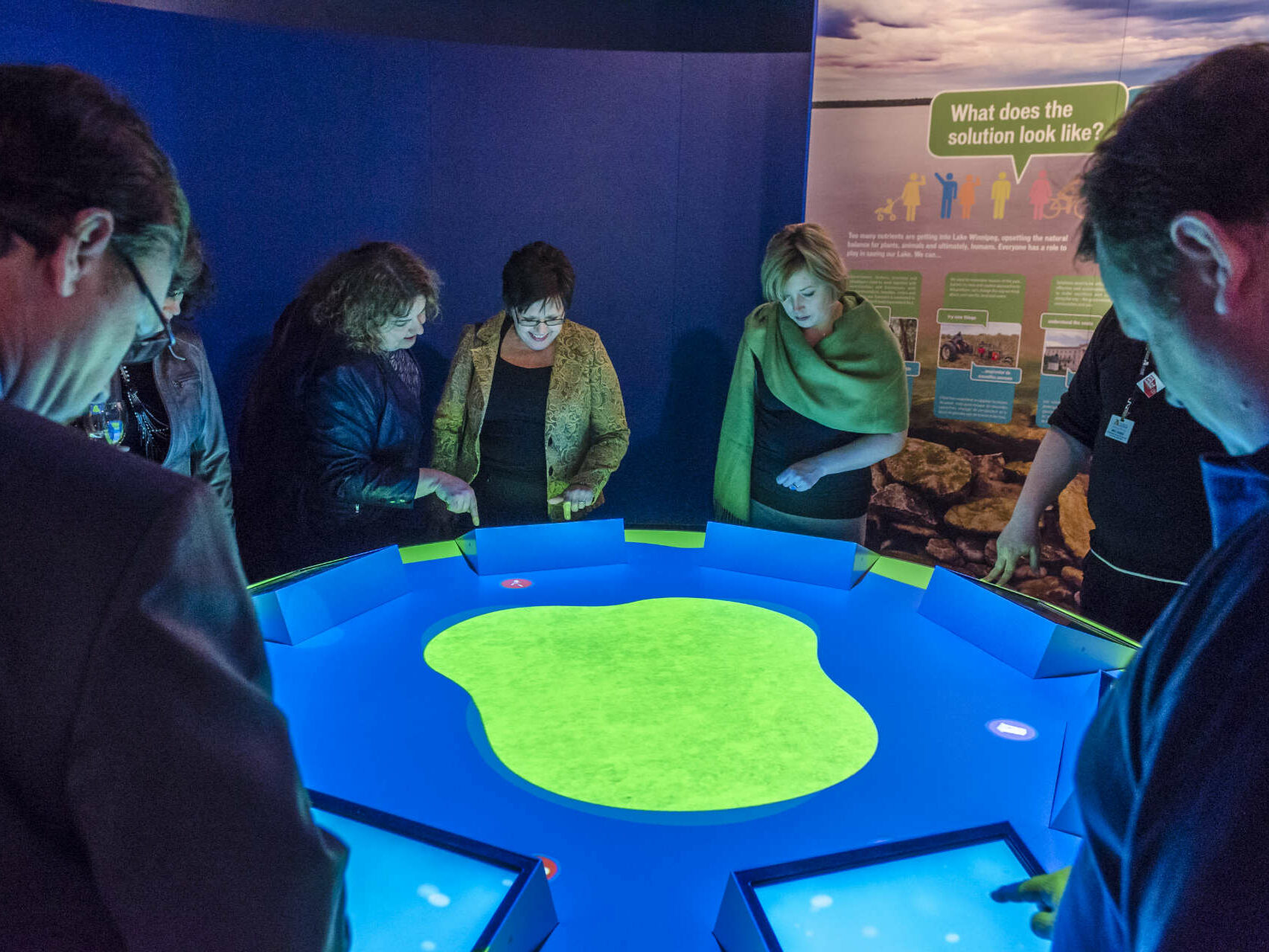 Group of adults interacting in the Lake Winnipeg display during a special event.