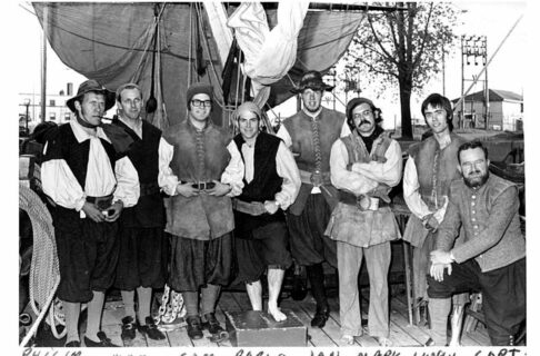 Eight men in old fashioned sailor outfits stand together posing for the camera on the deck of the Nonsuch. Along the bottom of the photo, aligning with each person, their names have been handwritten, “Philip, Max, Sam, Pablo, Jan, Mark, Hugh, Capt”.