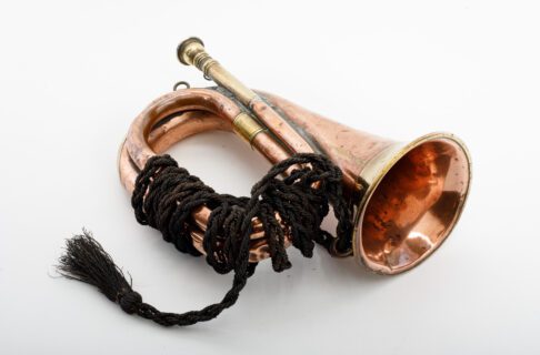 A small horn-shaped brass bugle with dark brown braided cord wrapped around the coil.