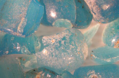 Microscopic image of broken and crazed blue coloured glass beads.