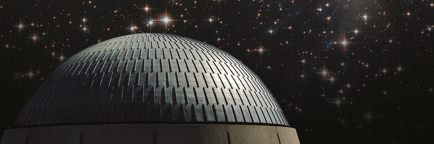 The exterior of the Planetarium dome in front of a starry night sky.