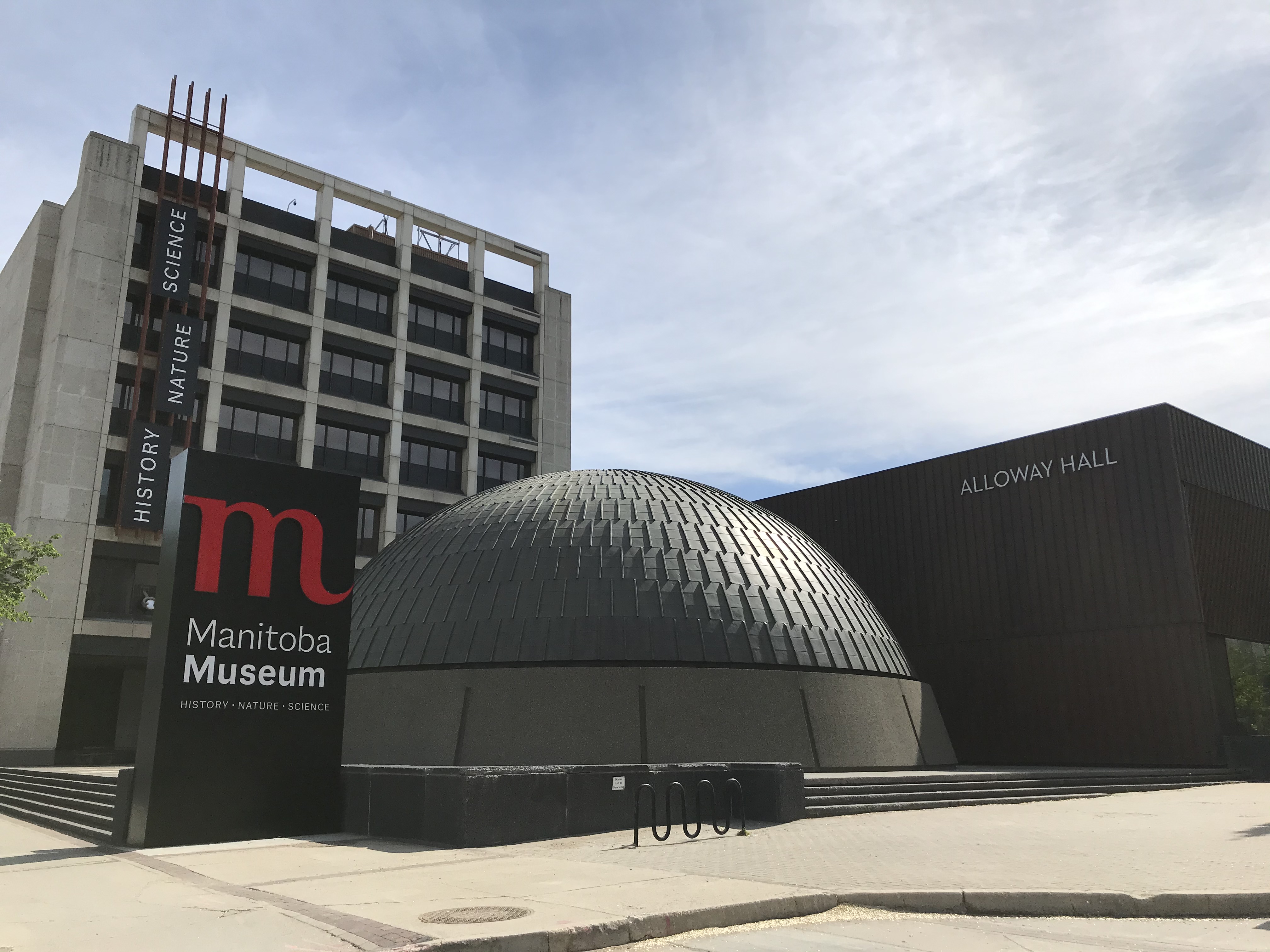 Exterior of the Manitoba Museum, with the Museum, Museum sign, and Planetarium dome in view.