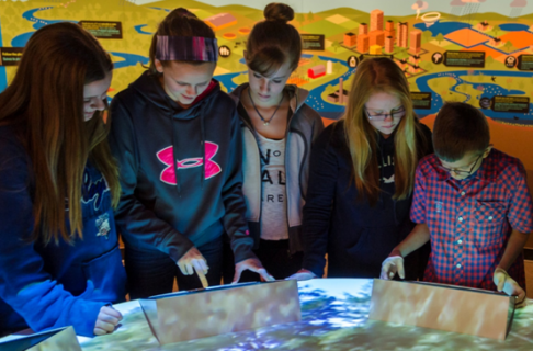 Five childrens looking at Winnipeg watershed ecosystem and interactive stream table.