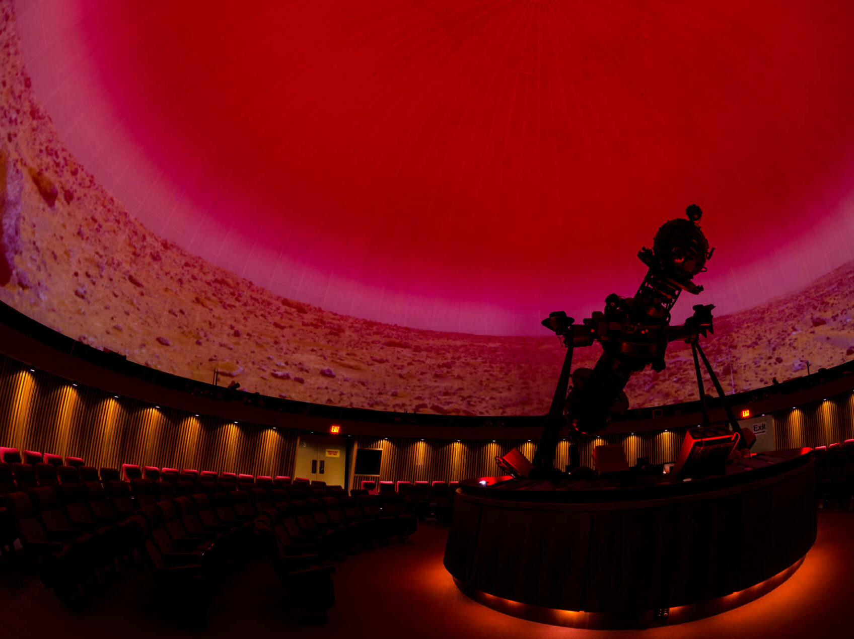 Interior shot of the Planetarium showing seating and Marvin with a the red sky and landscape of Mars being projected on the dome.