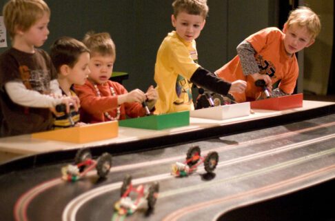 Five children playing at an electric car racetrack.
