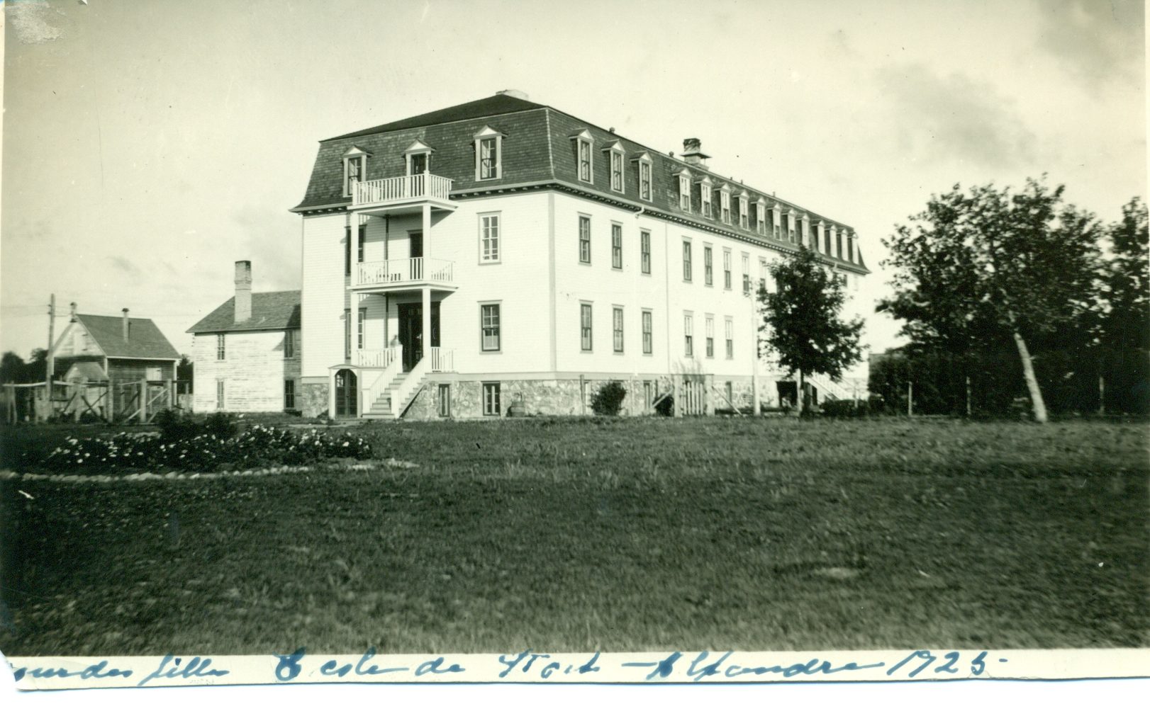Sepia photograph of a long three-storey building on a lawn.