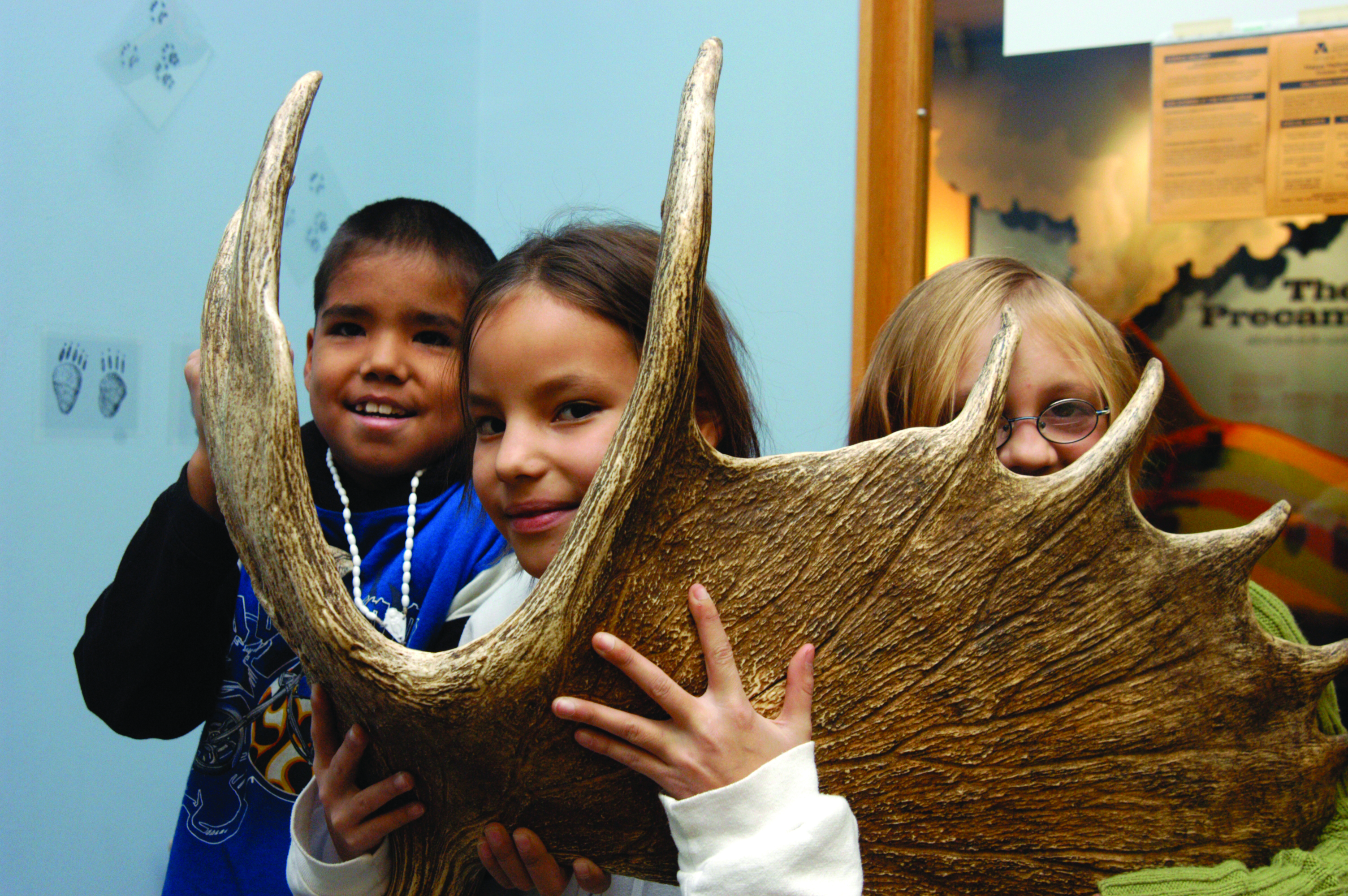 A three students peer through a moose antler.