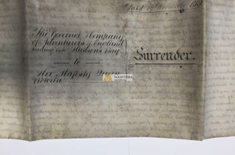 Photograph of the front side of a folded set of papers. Formal cursvie reads, “The Governor and Company of Adventurers of England trading into Hudson's Bay / to / Her Majesty Queen Victoria. / Surrender”. In the upper right corner reads, “Dated 19th November 1869”.