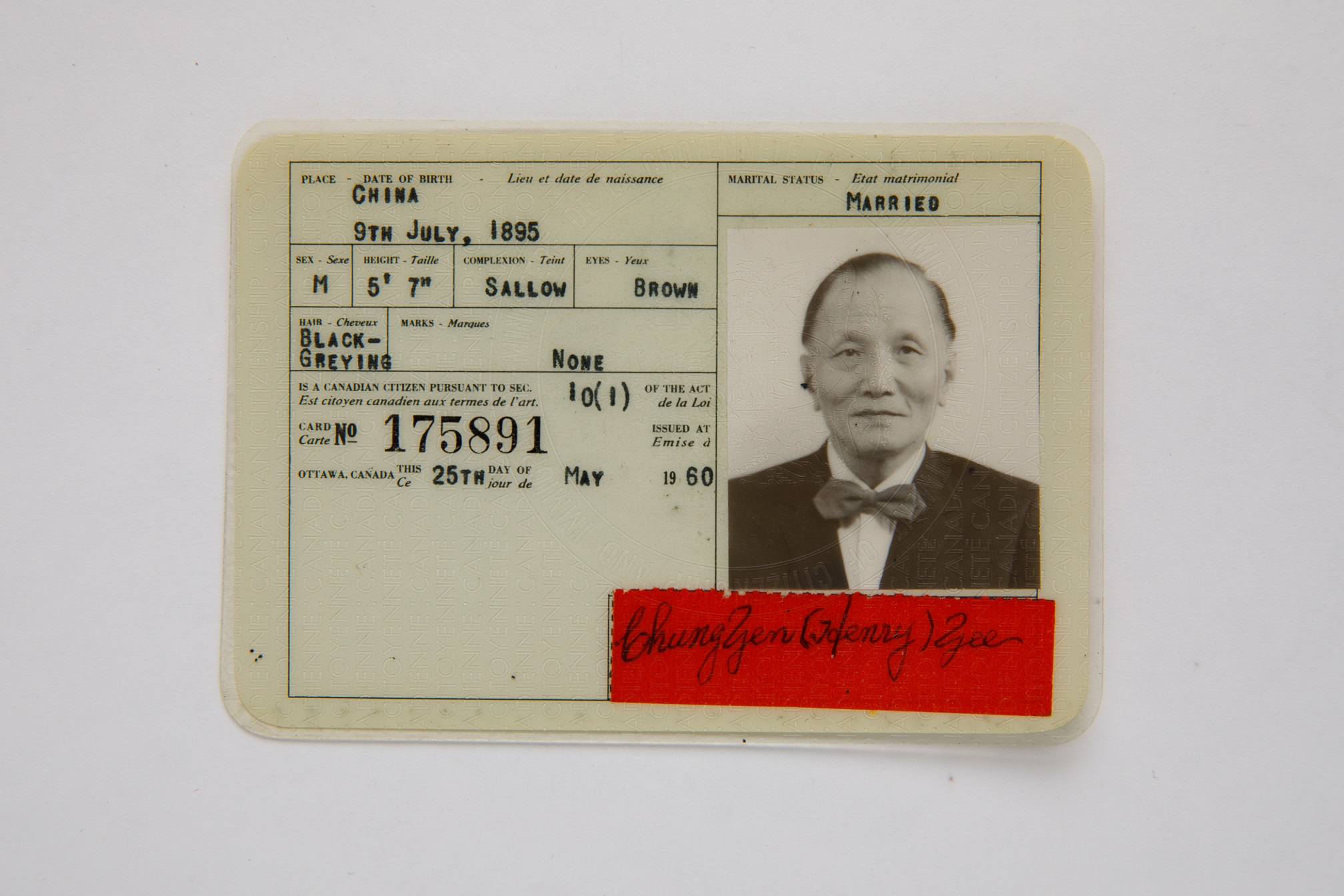 Photogragh of a citizenship card with identifiaction details and a photograph of an older man wearing a suit and bow tie.