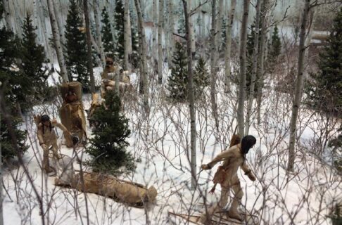 Close-up of a Museum diorama featuring members of an Anishnaabe family moving camp on snowshoes and sleds through a snowy forest.