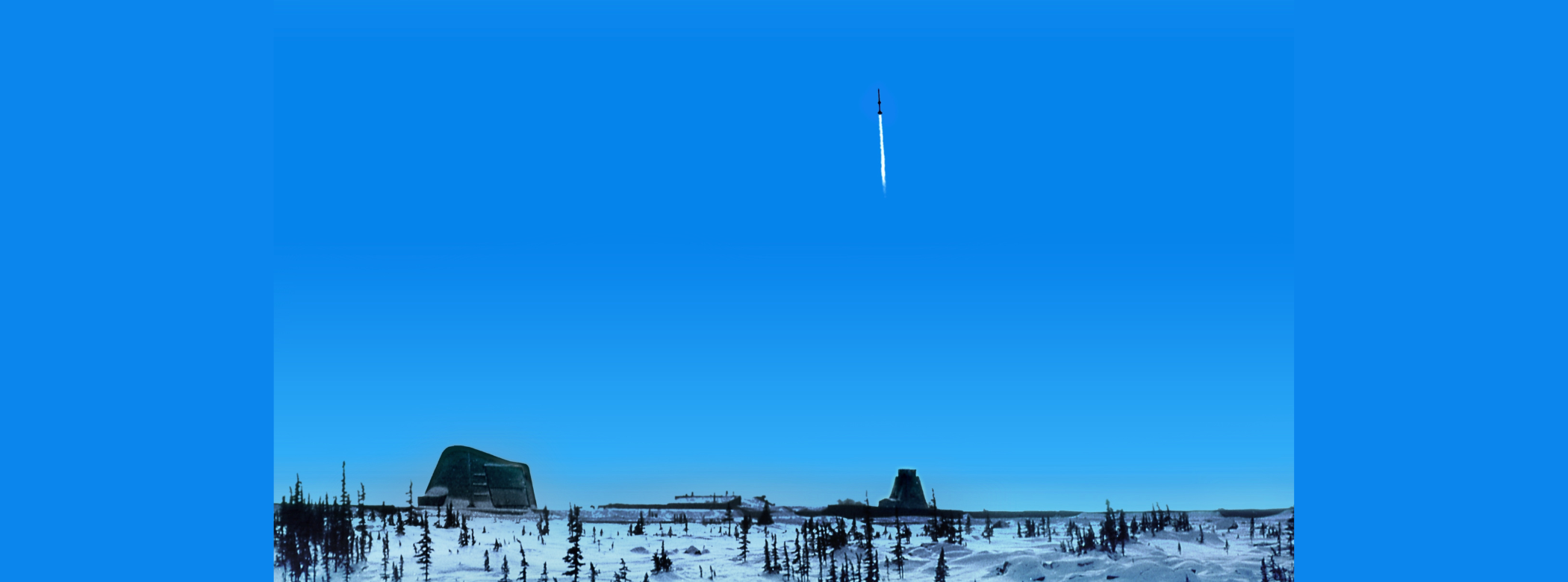 A two-stage rocket departs for space on a clear day in Churchill. A rocket rises up in a blue sky over snowy ground with clusters of trees.