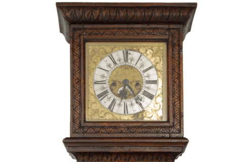 Close-up on the face of a brown wooden grandfather clock featuring intricate carving and a gold clock face.