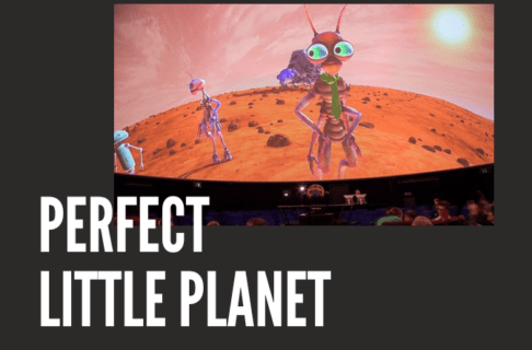 Photograph of a Planetarium Theatre screen showing several alien creatures on a dusty, red planet on a charcoal background. Text reads, "Perfect Little Planet".