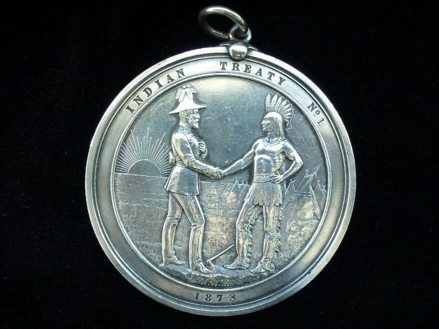 Image of Treaty 1 Medallion made of 99 per cent pure silver medal showing two individuals shaking hands.
