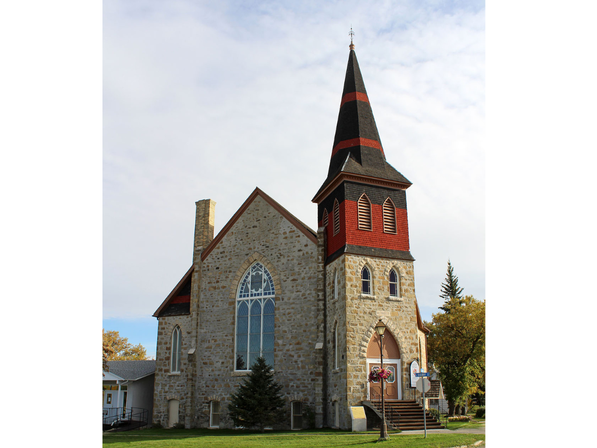 A church building built of varied fieldstone with a distinctive black and red steeple.