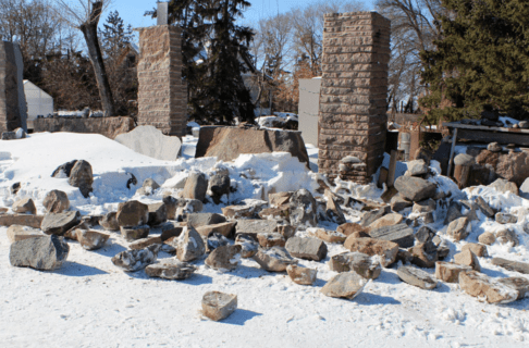 Large selection of blocks of fieldstone laid out in a cleared area on snowy ground.