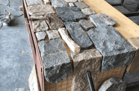 Thinned blocks of fieldstone being laid out on a section of metal frame.