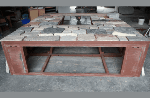 View underneath the 3-D metal frame, now lying flat with thinned fieldstone blocks placed on the surface. Inside it is hollow other than support beams.