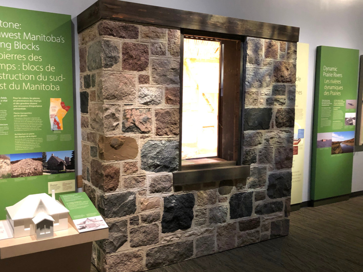 The constructed fieldstone wall in the new Prairies Gallery next to descriptive exhibit panels and other displays.