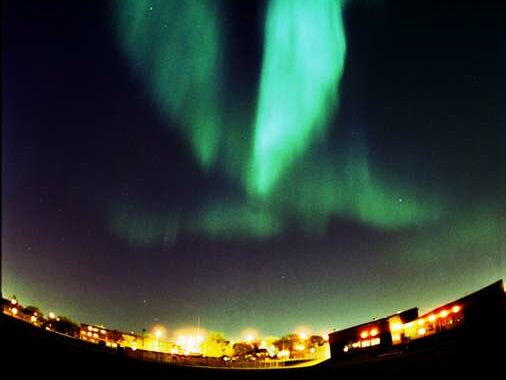 Northern lights above a city scape.