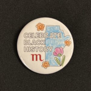 A button with a design featuring the shape of Manitoba and text reading "Celebrate Black History" above the Museum logo. The design is coloured in with pencil crayon.