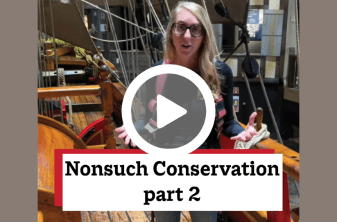 A screenshot of a video, an individual standing on the deck of a wooden ship. There's a play button over the screenshot and overlaid text reads, "Nonsuch Conservation part 2".
