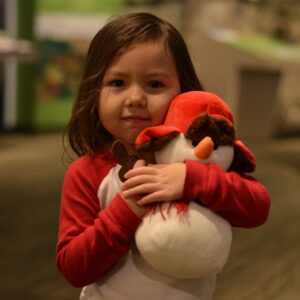 A photograph of a child hugging a stuffed snow person toy.