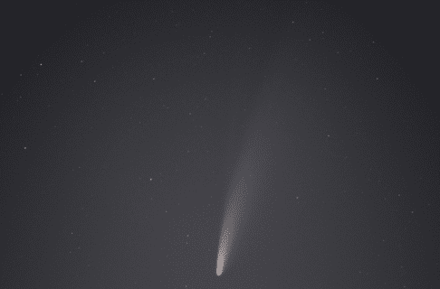 A comet streaking through the night sky, a white tail streaming out behind it.