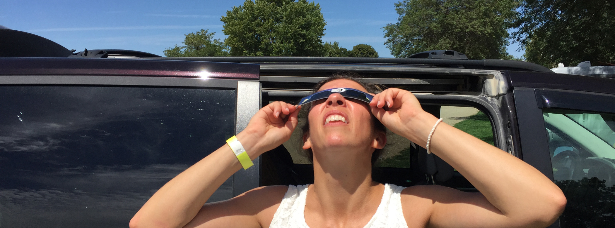 A woman observes a solar eclipse with safe eclipse glasses.