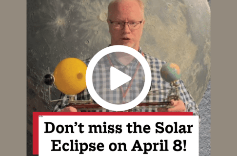 A screenshot of a video, an individual standing in front of a moon model, holding up a Sun, Moon, and Earth mobile. There's a play button over the screenshot and overlaid text reads, "Don't miss the Solar Eclipse on April 8!".