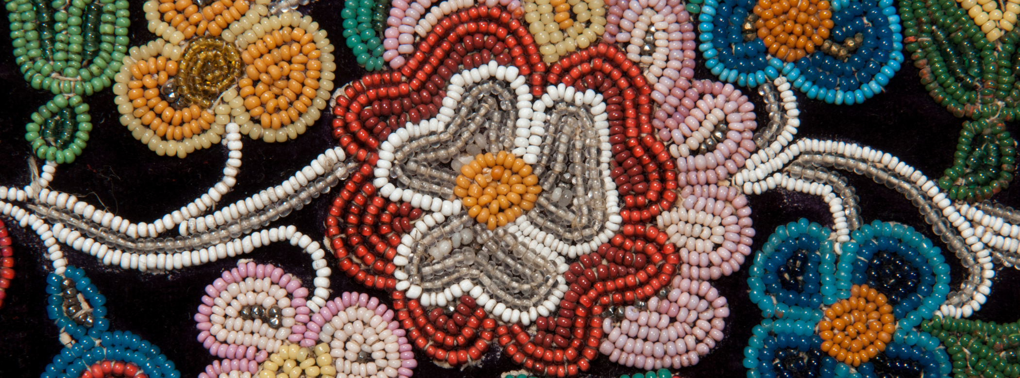 Close-up on a piece of colourful, intricate beadwork on a black background.