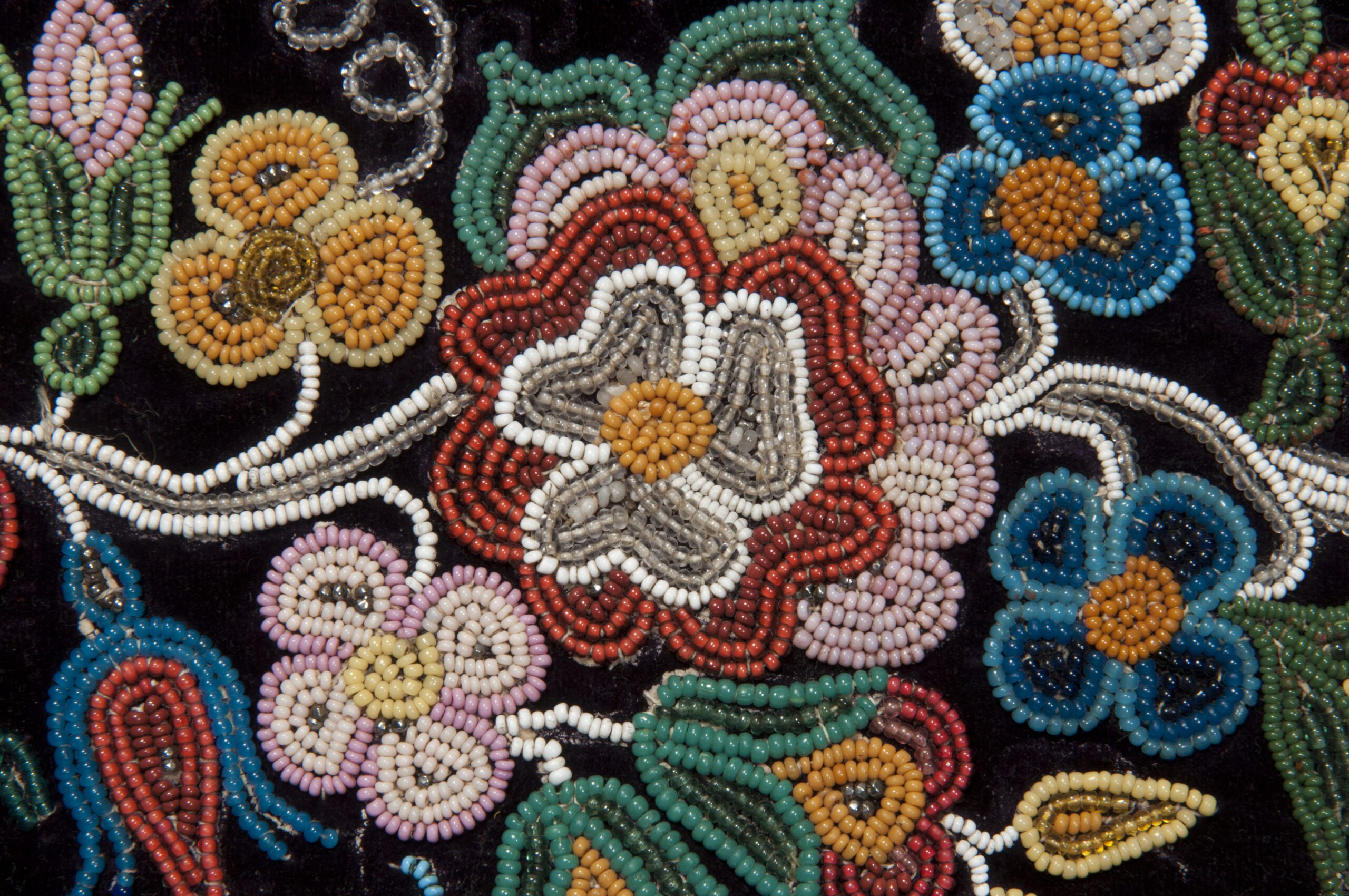 Close-up on a piece of colourful, intricate beadwork on a black background.