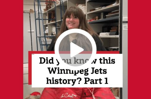 A screenshot of a video, an individual standing in museum collection storage holding up a red pair of hockey goalie's shorts. There's a play button over the screenshot and overlaid text reads, "Did you know this Winnipeg Jets history? Part 1".