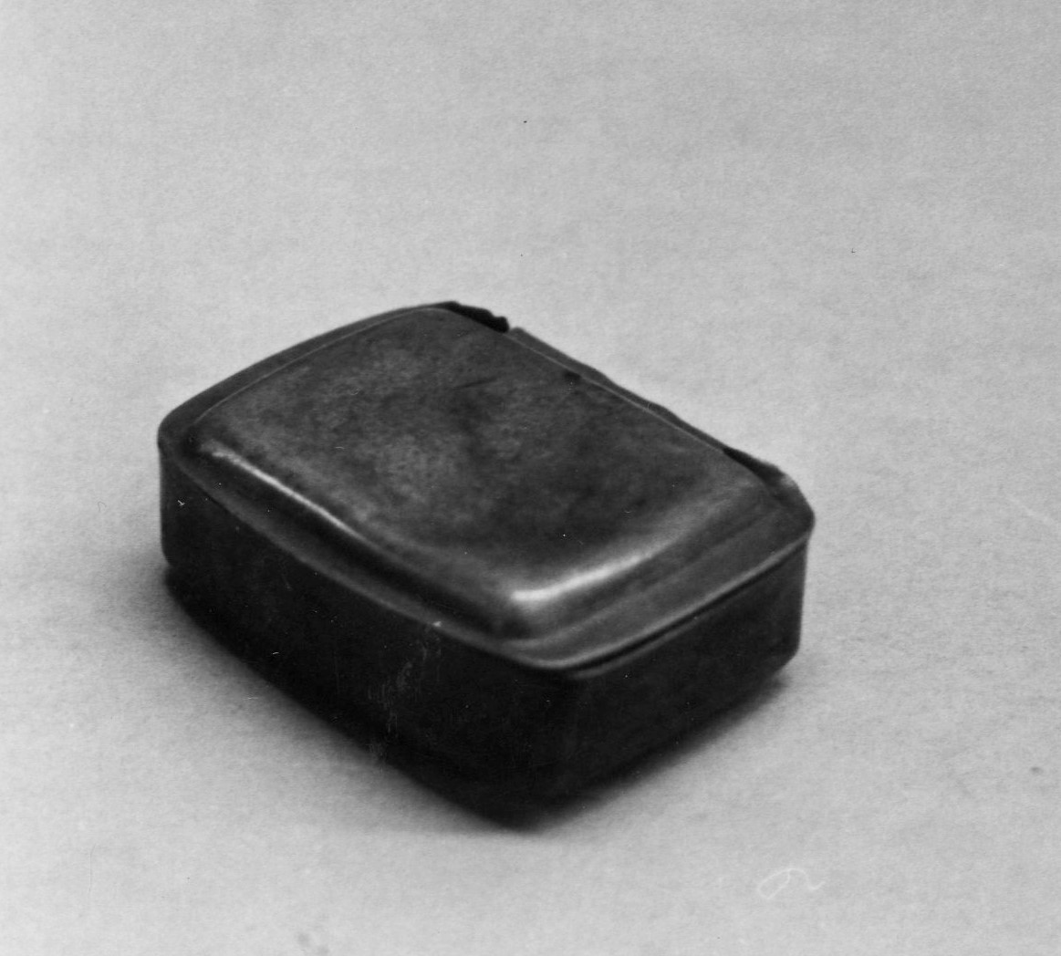 Black and white image of a black rectangular box with closed lid. 