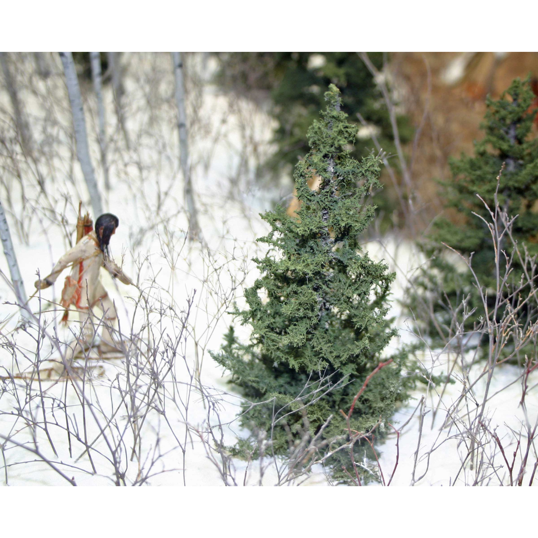 Close-up on a Museum mini diorama showing a person snowshoeing through a wooded area.