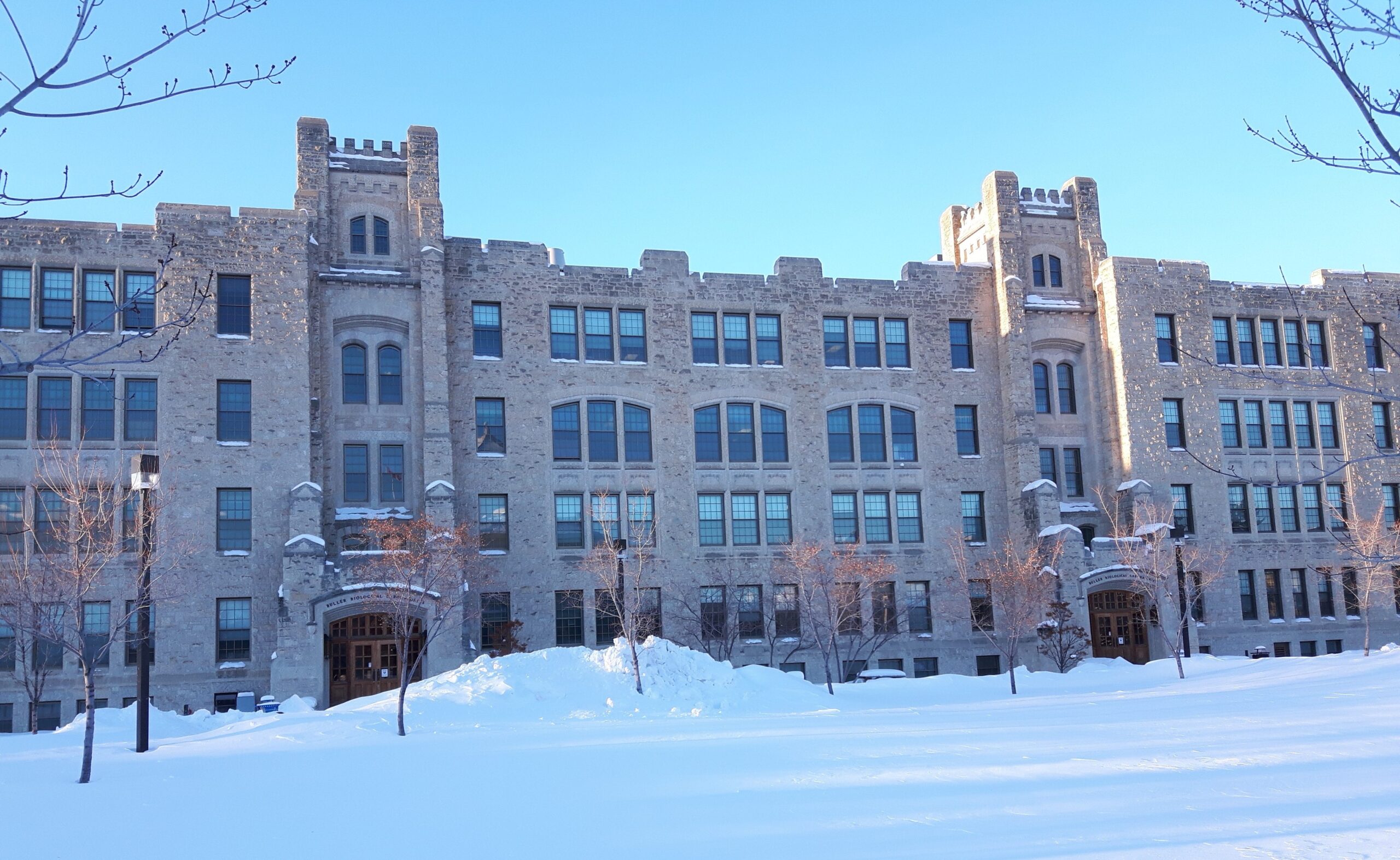 A large four-storey building built of light-coloured stone, with snow covering the grounds in front of it.