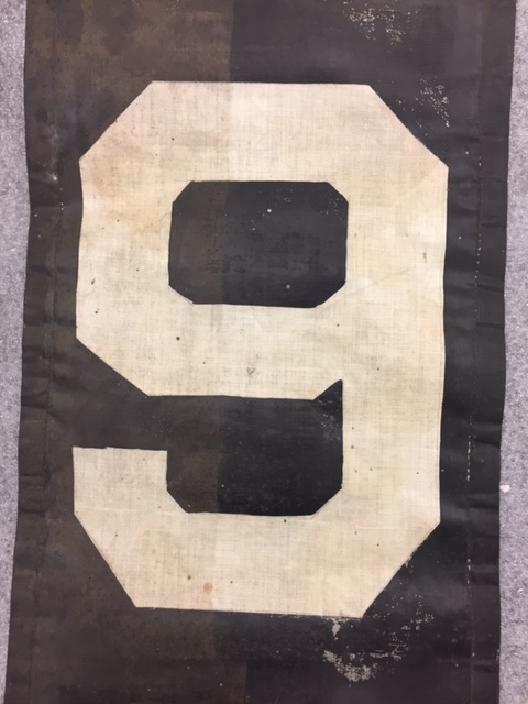 Close up on either a number 9 or 6 on a strip of fabric.