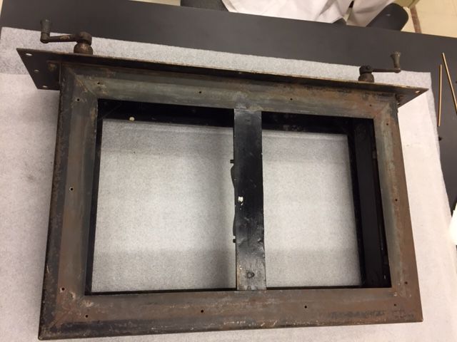 A rectangular streetcar sign frame laid on its back on protective foam, with the fabric rollers removed from the inside.