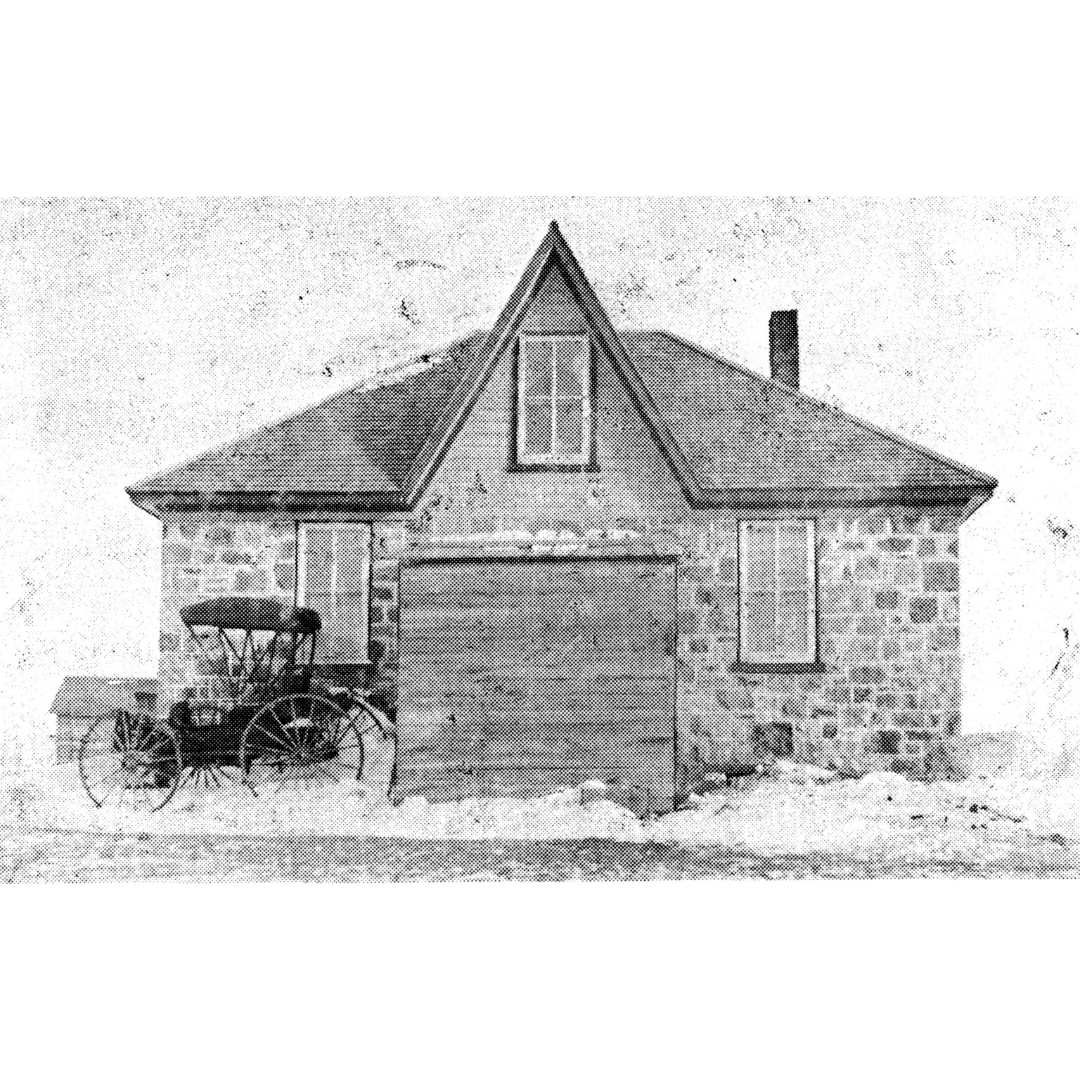 A weathered black and white photograph of a stone house with a buggy parked on the left side.