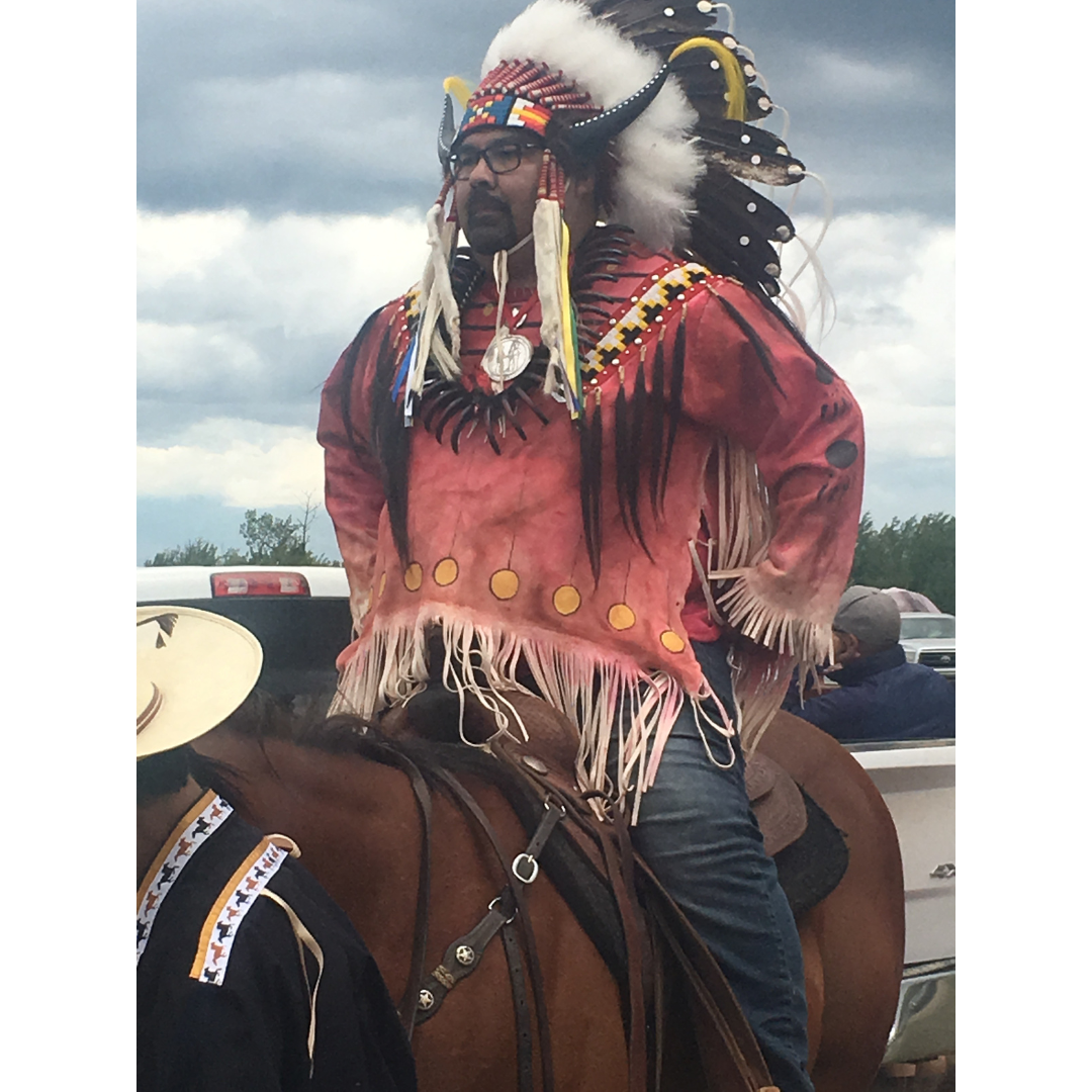 Red Pheasant Cree Nation Chief Clint Wuttunee riding a horse wearing a traditional headdress and the Treaty No. 6 medal.