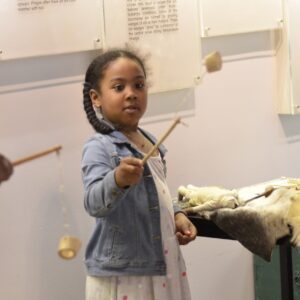 A child playing with a ring and pin game made from a stick and piece of antler in the Museum Galleries.