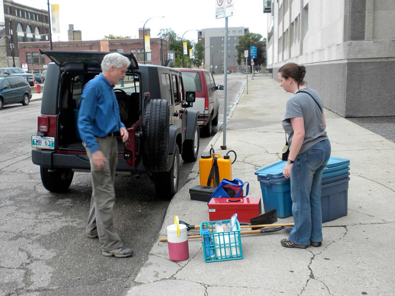 Two adults loading luggage and supplies into the back of a vehicle parked outside of the Museum.
