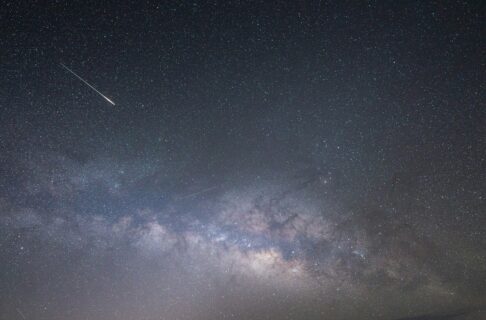 A meteor flashes across a starry sky.