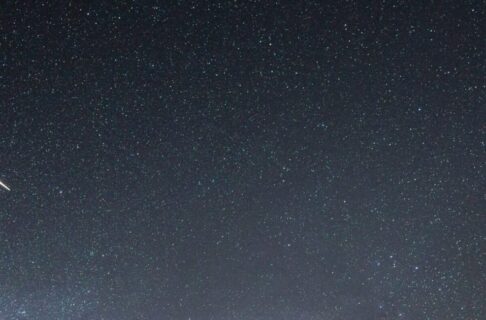 A meteor flashes across a starry sky.