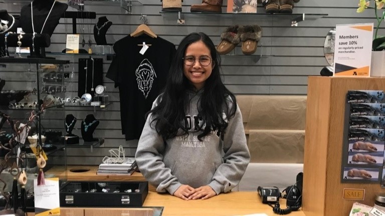 A smiling volunteer standing behind the counter in the Museum Shop.