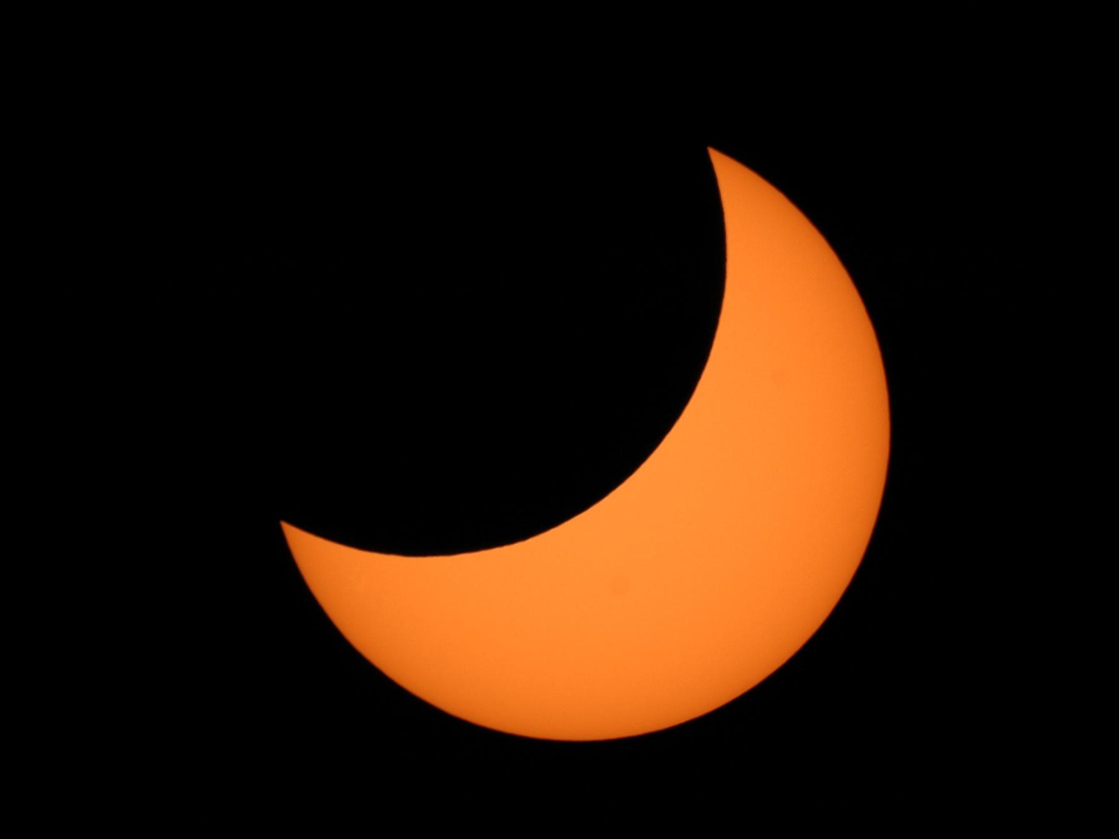 The Sun shown during a partial Solar Eclipse, half obstructed by the Moon.