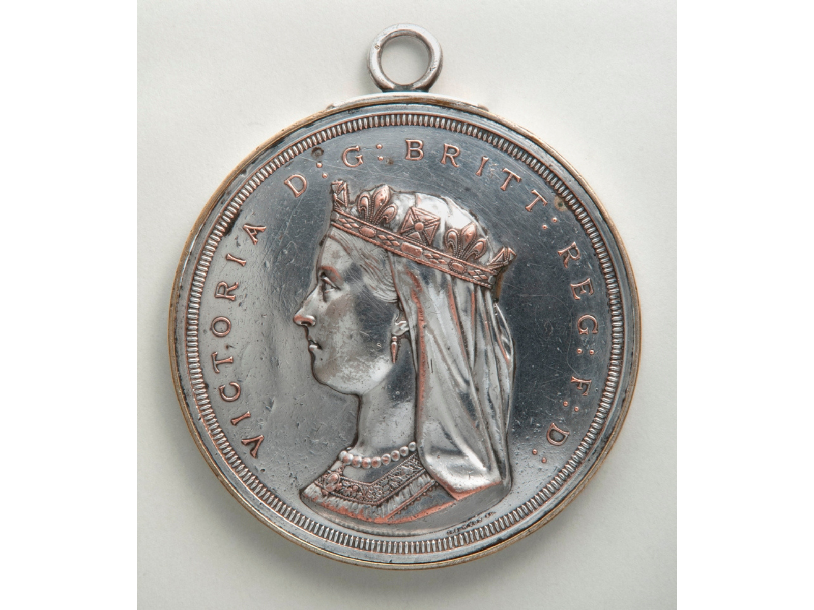 Obverse side of a Confederation medal showing a profile of Queen Victoria wearing a crown. Text encircling her on the medal reads, "VICTORIA D: G: BRIT: REG: F: D:".